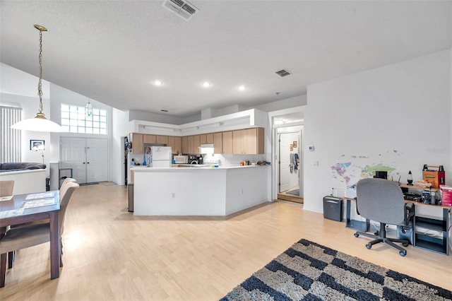 kitchen with visible vents, open floor plan, brown cabinets, freestanding refrigerator, and light countertops