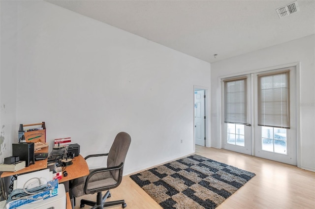 office with french doors, light wood-type flooring, and visible vents