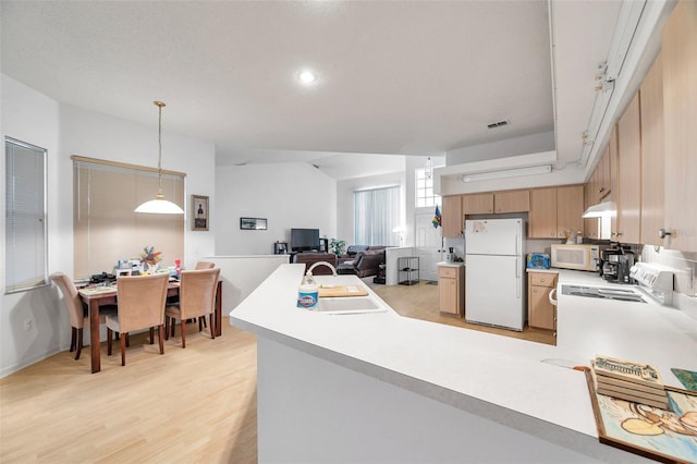 kitchen with decorative light fixtures, light countertops, open floor plan, a sink, and white appliances