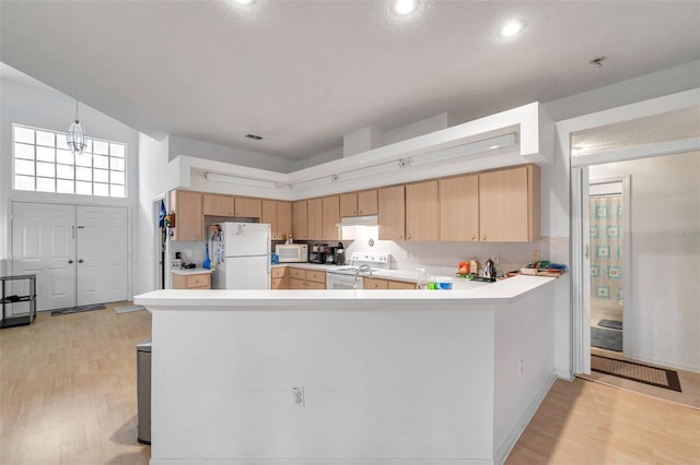 kitchen featuring light countertops, white appliances, light wood-type flooring, and a peninsula