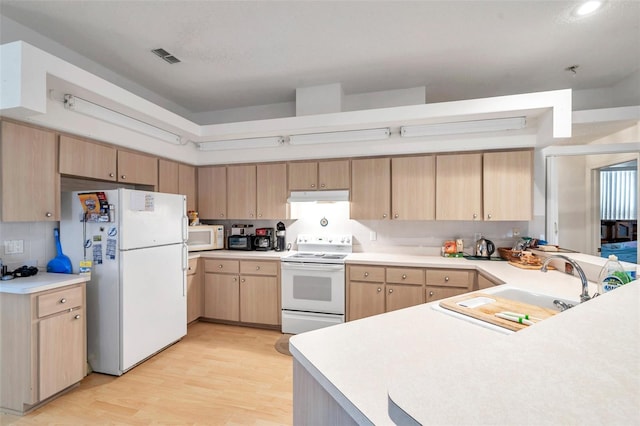 kitchen with light countertops, light brown cabinetry, a sink, white appliances, and under cabinet range hood