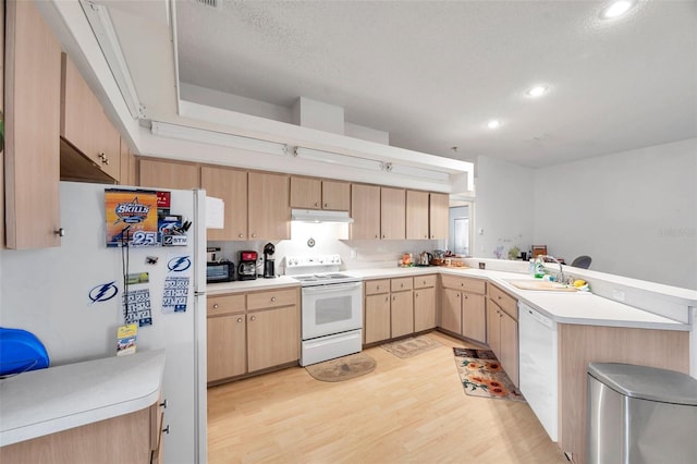 kitchen featuring white appliances, light brown cabinets, under cabinet range hood, and light countertops