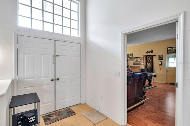 entryway featuring baseboards, light wood-style flooring, and a towering ceiling