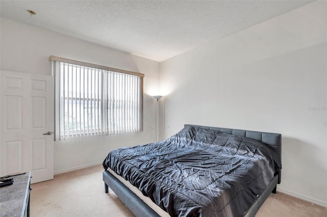 bedroom featuring a textured ceiling, baseboards, and light colored carpet