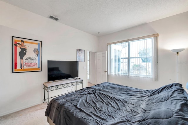 carpeted bedroom featuring visible vents, a textured ceiling, and baseboards