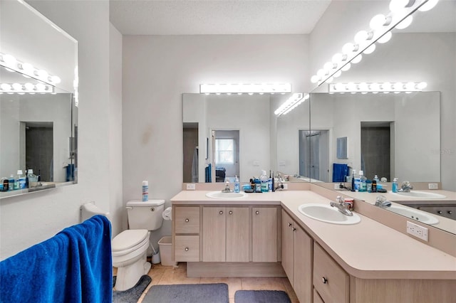 bathroom with toilet, vanity, a textured ceiling, and tile patterned floors