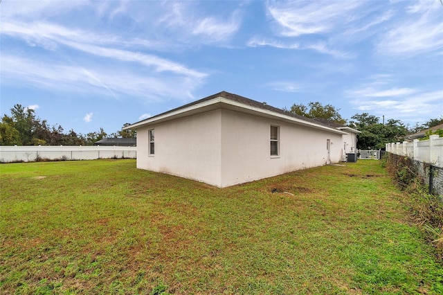 view of side of property featuring a fenced backyard, a lawn, central AC, and stucco siding