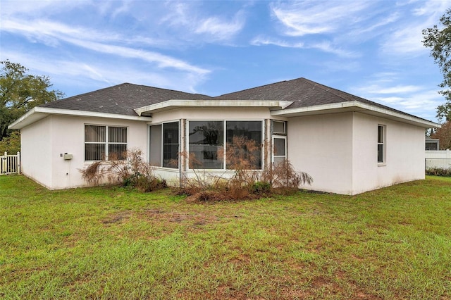 back of property with roof with shingles, a lawn, fence, and stucco siding