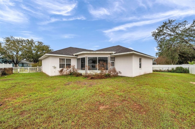 back of house with a fenced backyard, a lawn, and stucco siding