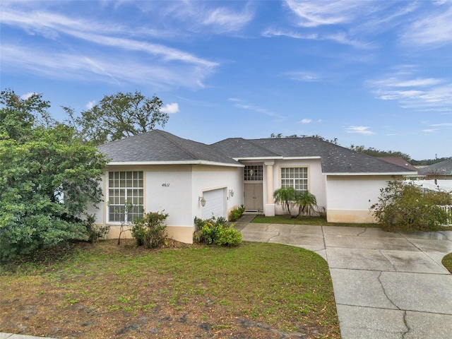 ranch-style home with stucco siding, a shingled roof, an attached garage, driveway, and a front lawn