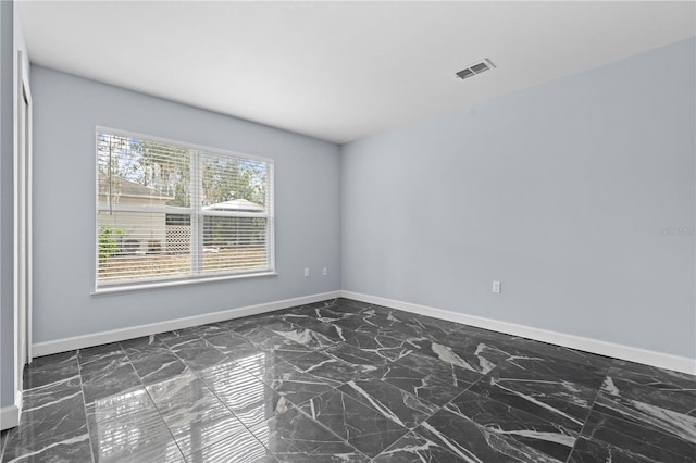 empty room with baseboards, visible vents, and marble finish floor