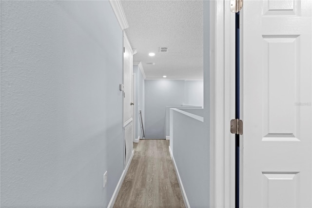 hallway with baseboards, ornamental molding, an upstairs landing, wood finished floors, and a textured ceiling