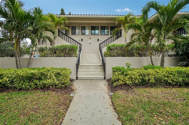 view of front of house with stairs, a fenced front yard, and stucco siding