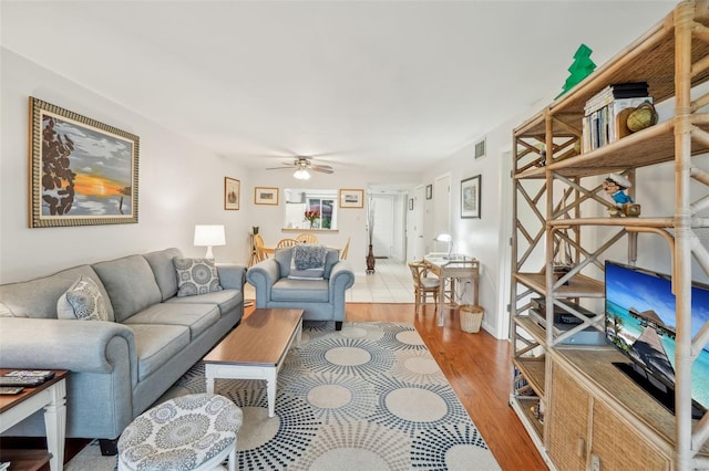 living area with light wood-style flooring, visible vents, and ceiling fan