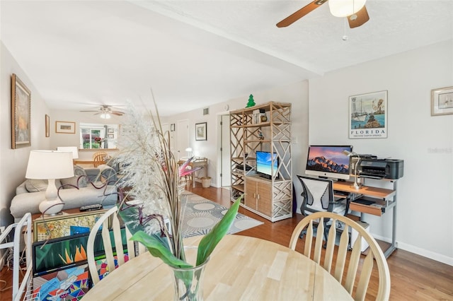 dining space with baseboards, a ceiling fan, and wood finished floors