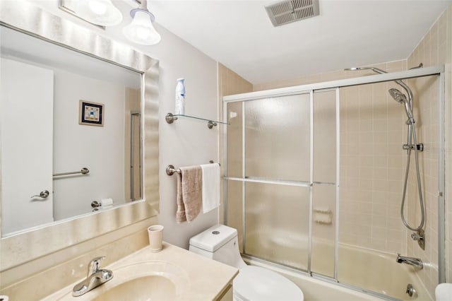 full bathroom with visible vents, vanity, toilet, and combined bath / shower with glass door