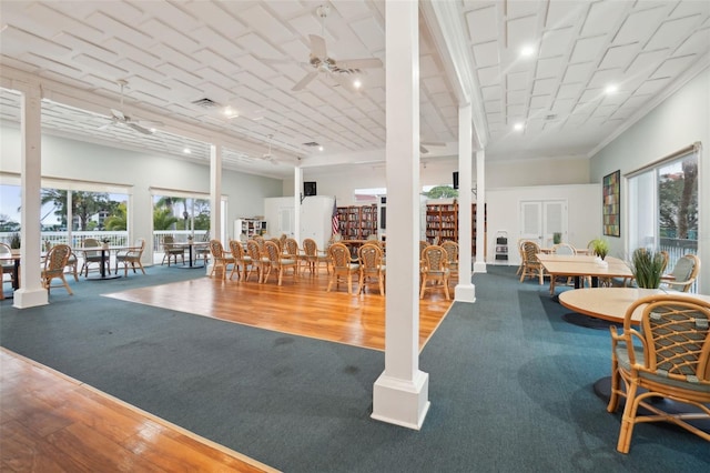 interior space with a ceiling fan, decorative columns, and wood finished floors