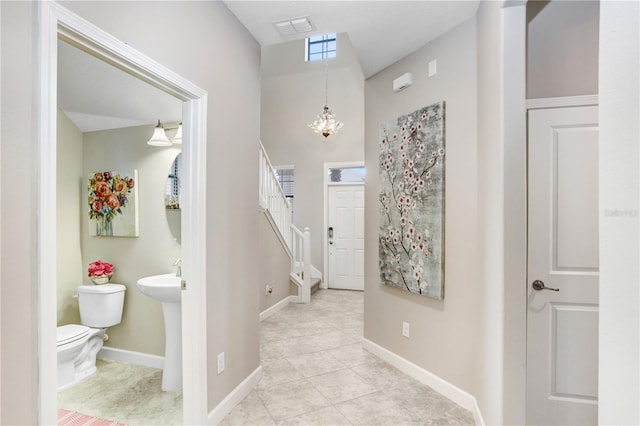 interior space with light tile patterned floors, baseboards, visible vents, stairs, and a chandelier