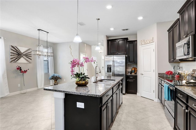 kitchen featuring stainless steel appliances, a sink, visible vents, hanging light fixtures, and an island with sink