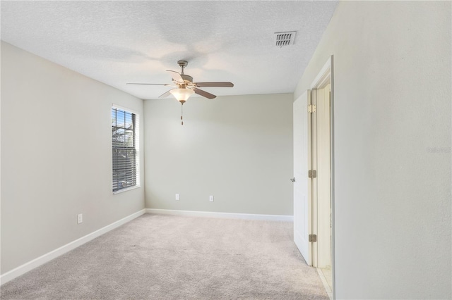 spare room featuring visible vents, a ceiling fan, light carpet, a textured ceiling, and baseboards