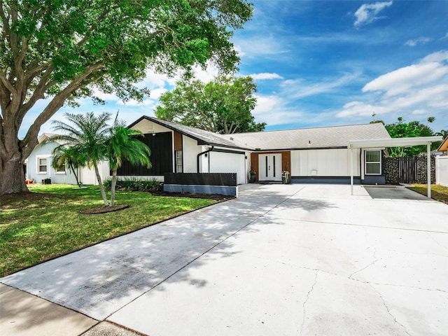 view of front of house featuring an attached carport, an attached garage, driveway, and a front lawn