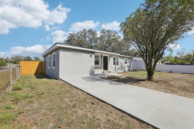 ranch-style home with a front yard, fence, and stucco siding