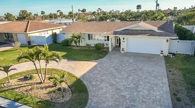 ranch-style house with decorative driveway, a gate, fence, a garage, and a front lawn