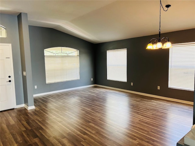 empty room featuring a chandelier, lofted ceiling, dark wood finished floors, and plenty of natural light