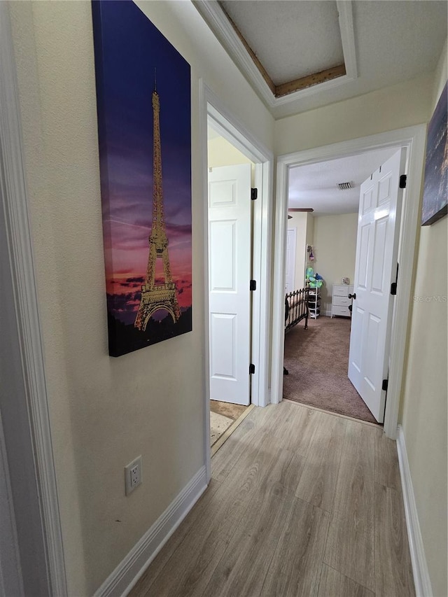 hallway with visible vents, baseboards, and wood finished floors