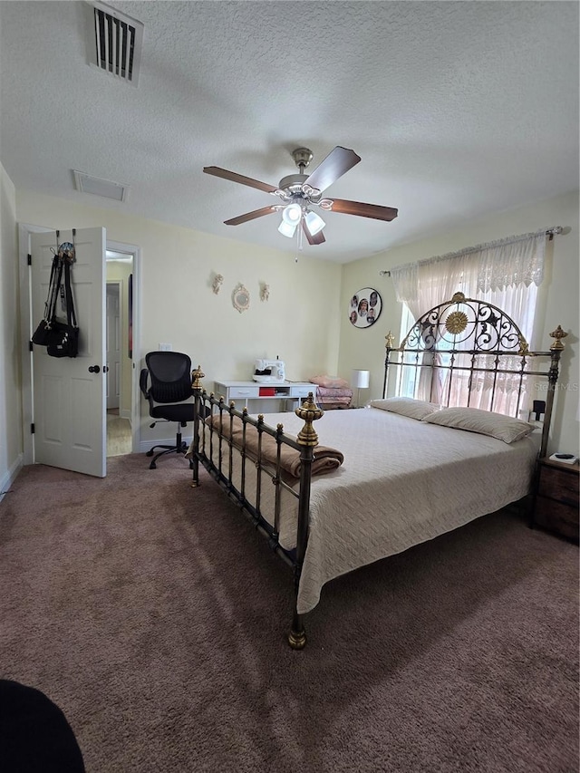 bedroom with a textured ceiling, ceiling fan, visible vents, baseboards, and dark colored carpet