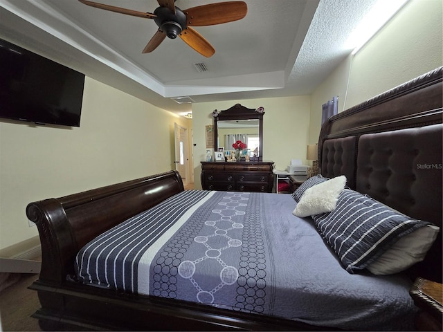 bedroom featuring a ceiling fan, visible vents, and a tray ceiling