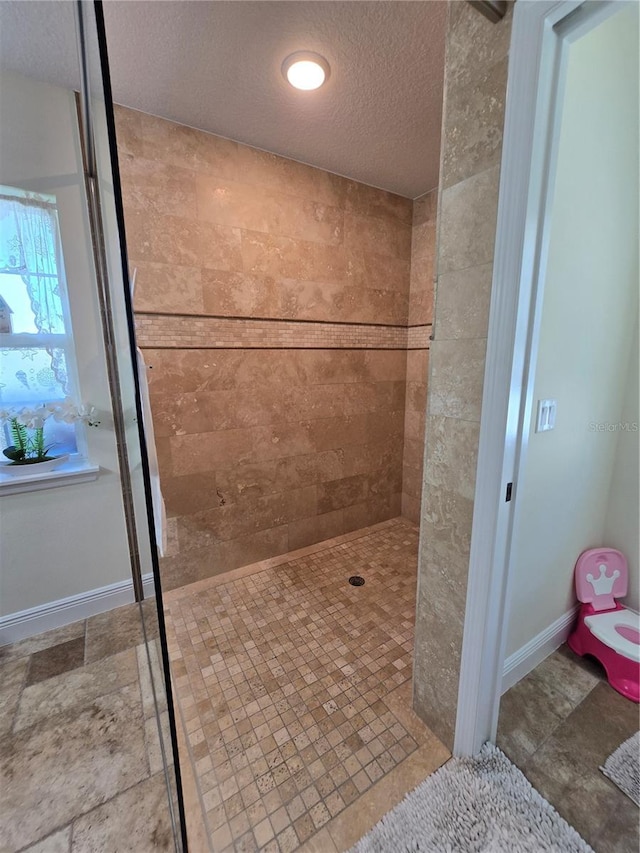 full bathroom featuring a textured ceiling, baseboards, and a walk in shower