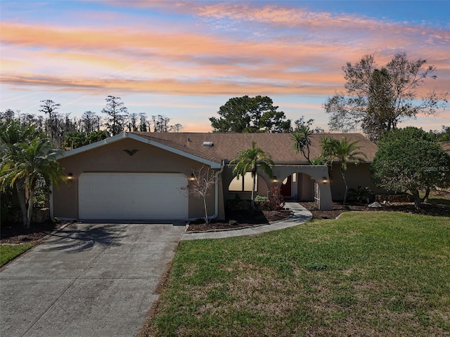 view of front facade with driveway, an attached garage, a front yard, and stucco siding