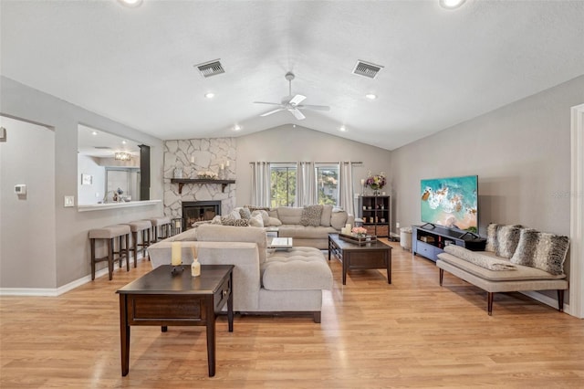 living area featuring lofted ceiling, a fireplace, visible vents, and light wood-style floors