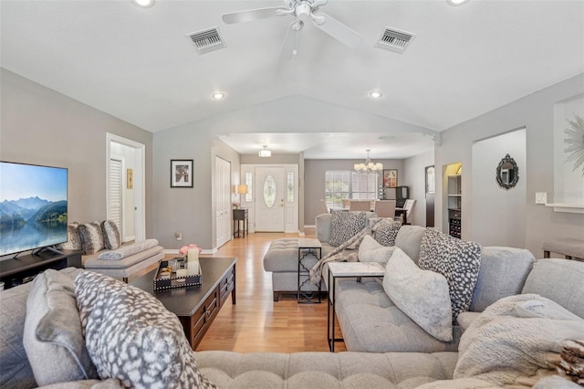 living area featuring light wood-type flooring, visible vents, vaulted ceiling, and ceiling fan with notable chandelier