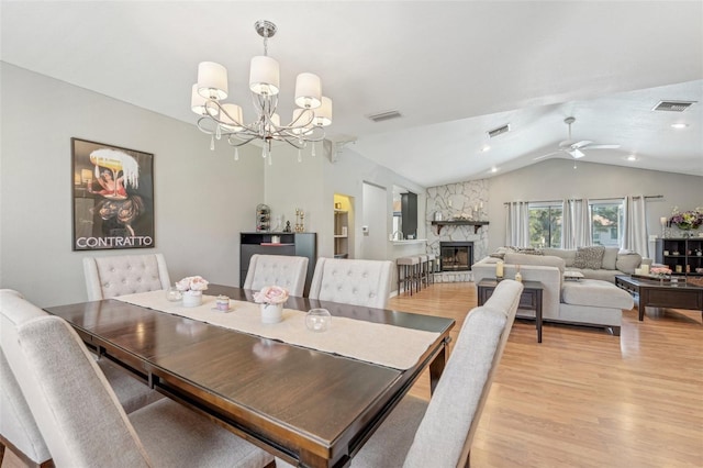 dining space featuring lofted ceiling, visible vents, a fireplace, and light wood-style flooring