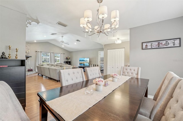 dining room with lofted ceiling, light wood-type flooring, visible vents, and ceiling fan with notable chandelier