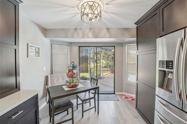 dining room featuring light wood-style floors, a chandelier, and baseboards