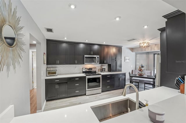 kitchen featuring stainless steel appliances, light countertops, a sink, and visible vents