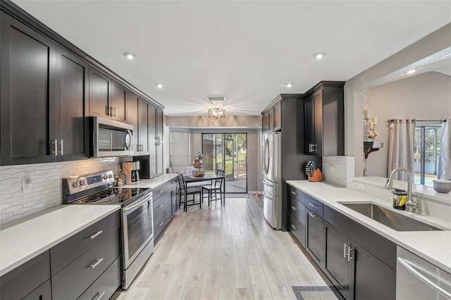 kitchen featuring stainless steel appliances, plenty of natural light, a sink, and light countertops