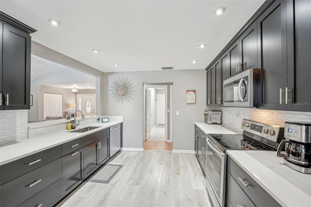 kitchen with a sink, visible vents, light wood-style floors, light countertops, and appliances with stainless steel finishes