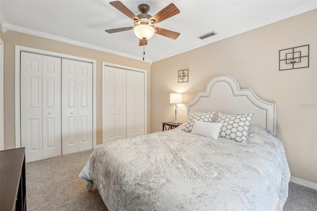 carpeted bedroom with a ceiling fan, visible vents, two closets, and ornamental molding