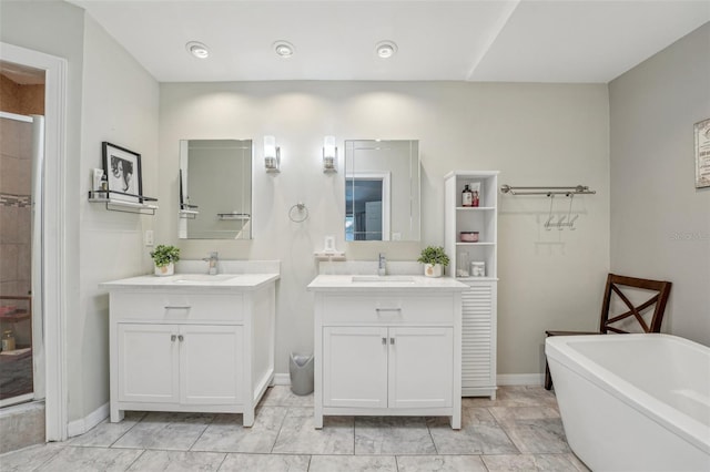 full bathroom with a freestanding bath, two vanities, and a sink