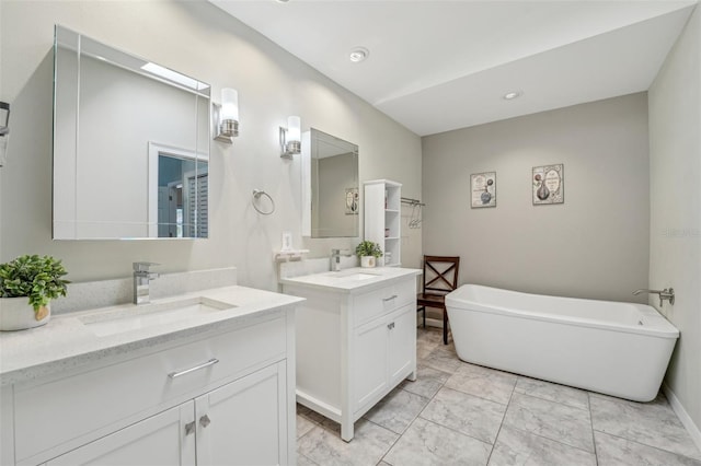 bathroom with a soaking tub, baseboards, two vanities, and a sink