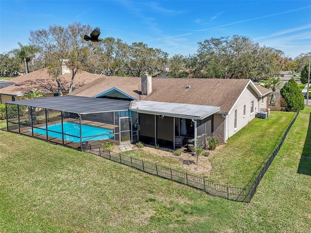 back of property with a fenced in pool, a lanai, a lawn, and a chimney