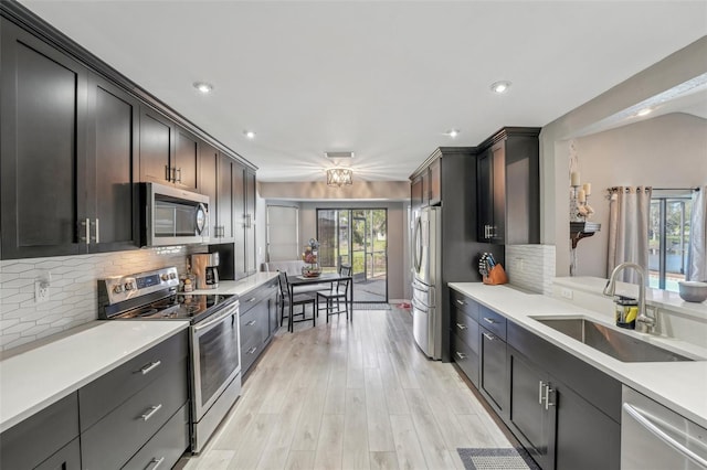 kitchen with a sink, backsplash, appliances with stainless steel finishes, and a healthy amount of sunlight