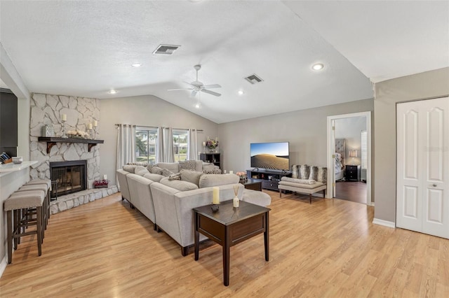 living area featuring light wood-style floors, visible vents, vaulted ceiling, and ceiling fan