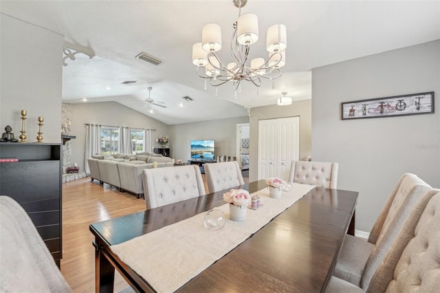 dining room featuring visible vents, light wood finished floors, lofted ceiling, and ceiling fan with notable chandelier