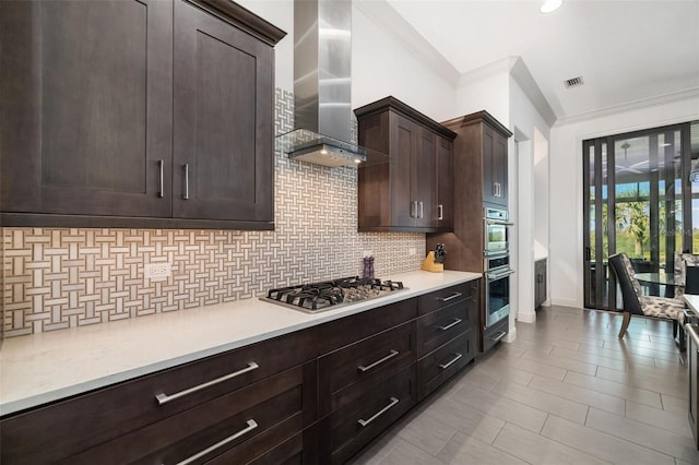 kitchen with wall chimney range hood, stainless steel appliances, visible vents, and light countertops