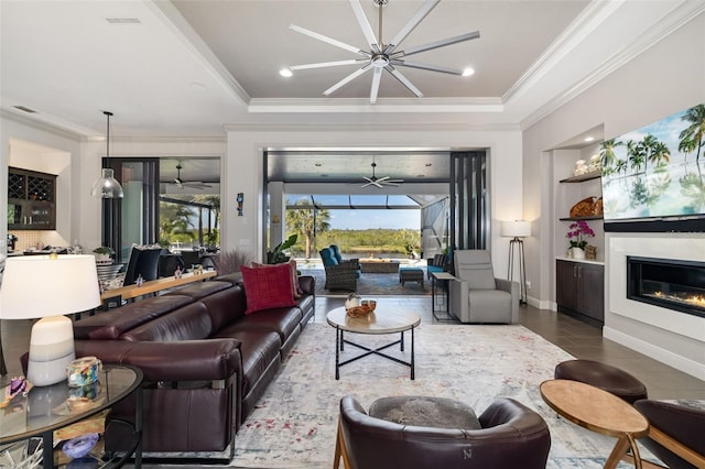 living room with a sunroom, built in shelves, a glass covered fireplace, and a wealth of natural light